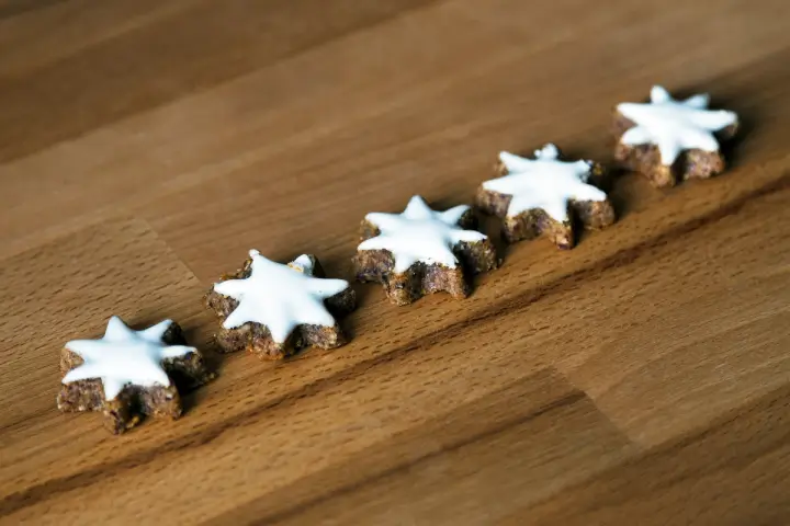 Five iced star cookies lined up in a row on a table